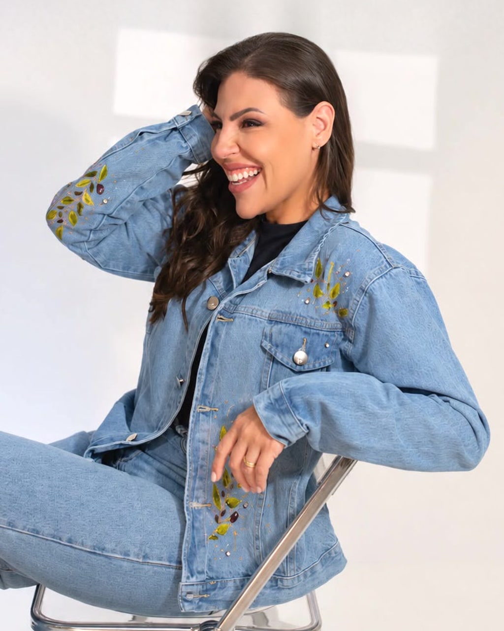 Mulher sorrindo com jaqueta jeans R U T H. com folhas bordadas e pintadas à mão na manga e na frente